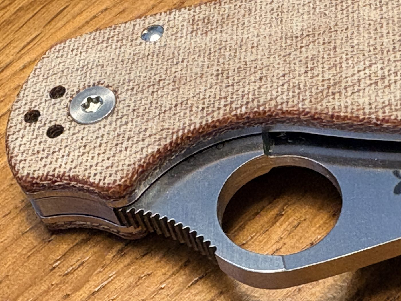 Two folding knives side by side on a wooden surface