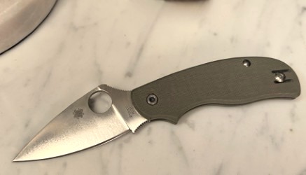 A Spyderco slip joint knife open on a marble surface
